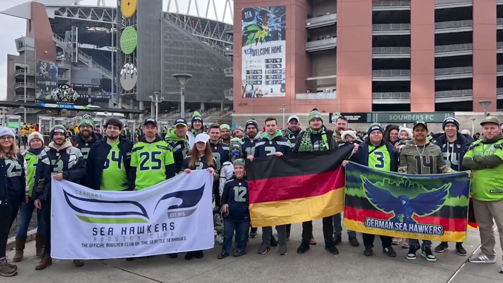 German Seahawks Booster Club fans with flags at Lumen Field stadium.