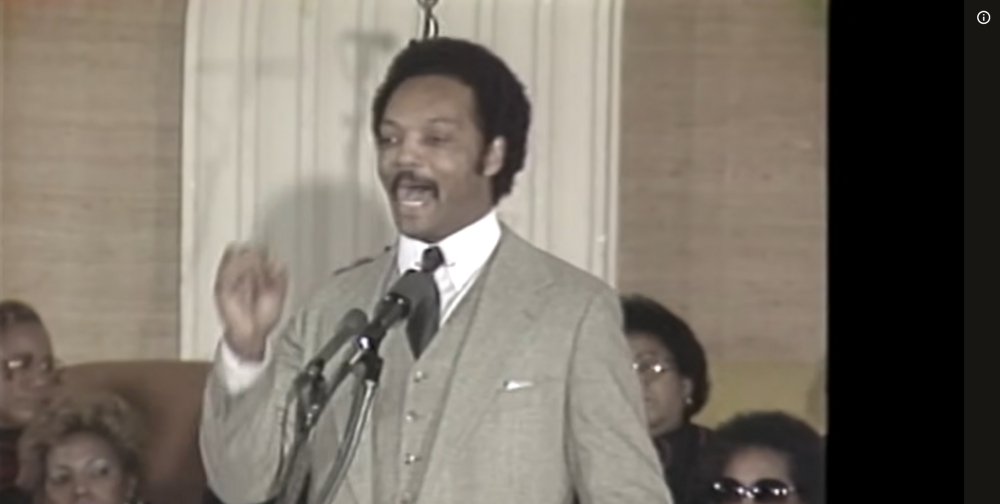 James Brown speaking passionately at microphone in suit